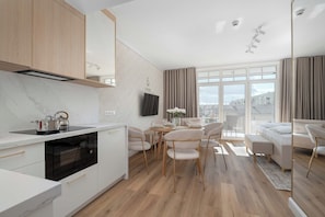 Eine moderne Küche mit Backofen, ein Essbereich mit Tisch und Stühlen sowie ein Wohnzimmer mit Sofa und Blick auf die Stadt.