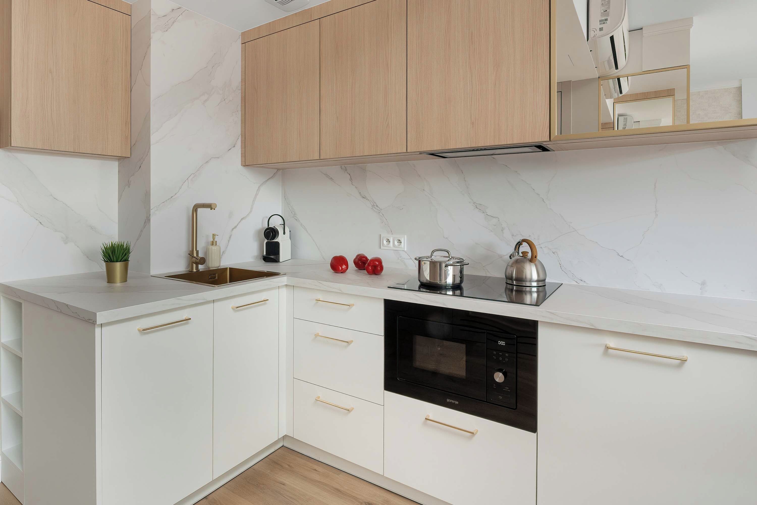 Eine moderne Küche mit weißen Schränken, einer Marmor-Spritzschutzleiste, einem eingebauten Backofen und einer Edelstahl-Dunstabzugshaube.