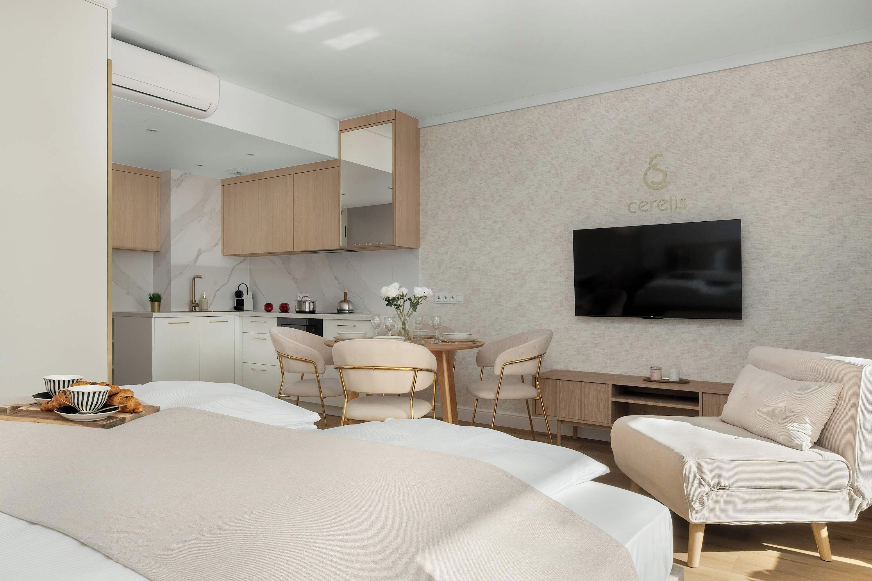 Una habitación de hotel moderna con cama, zona de comedor, televisor y kitchenette.