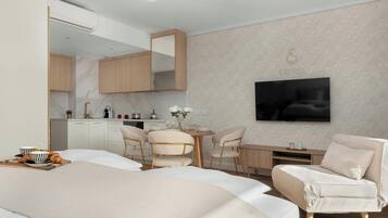 Una habitación de hotel moderna con cama, zona de comedor, televisor y kitchenette.