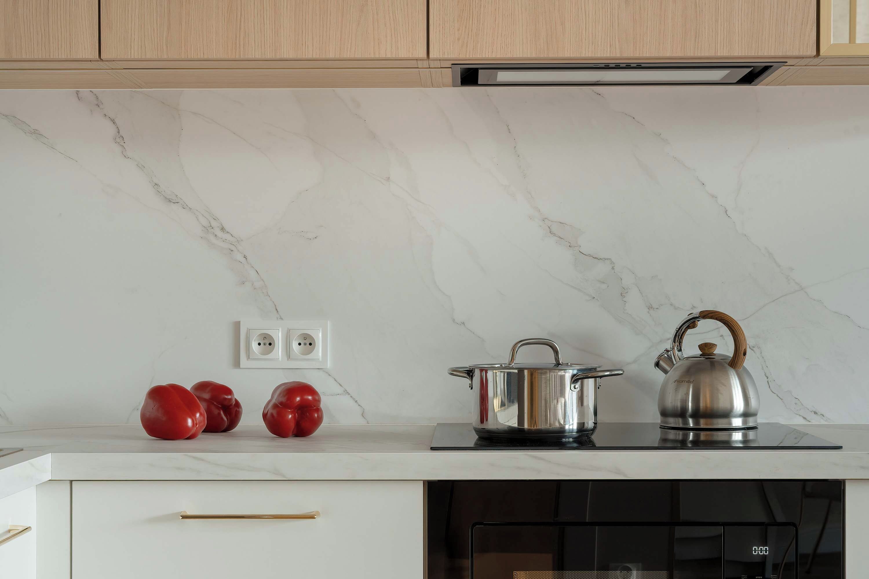 A kitchen with a marble backsplash, a stove, a kettle, and a pot.