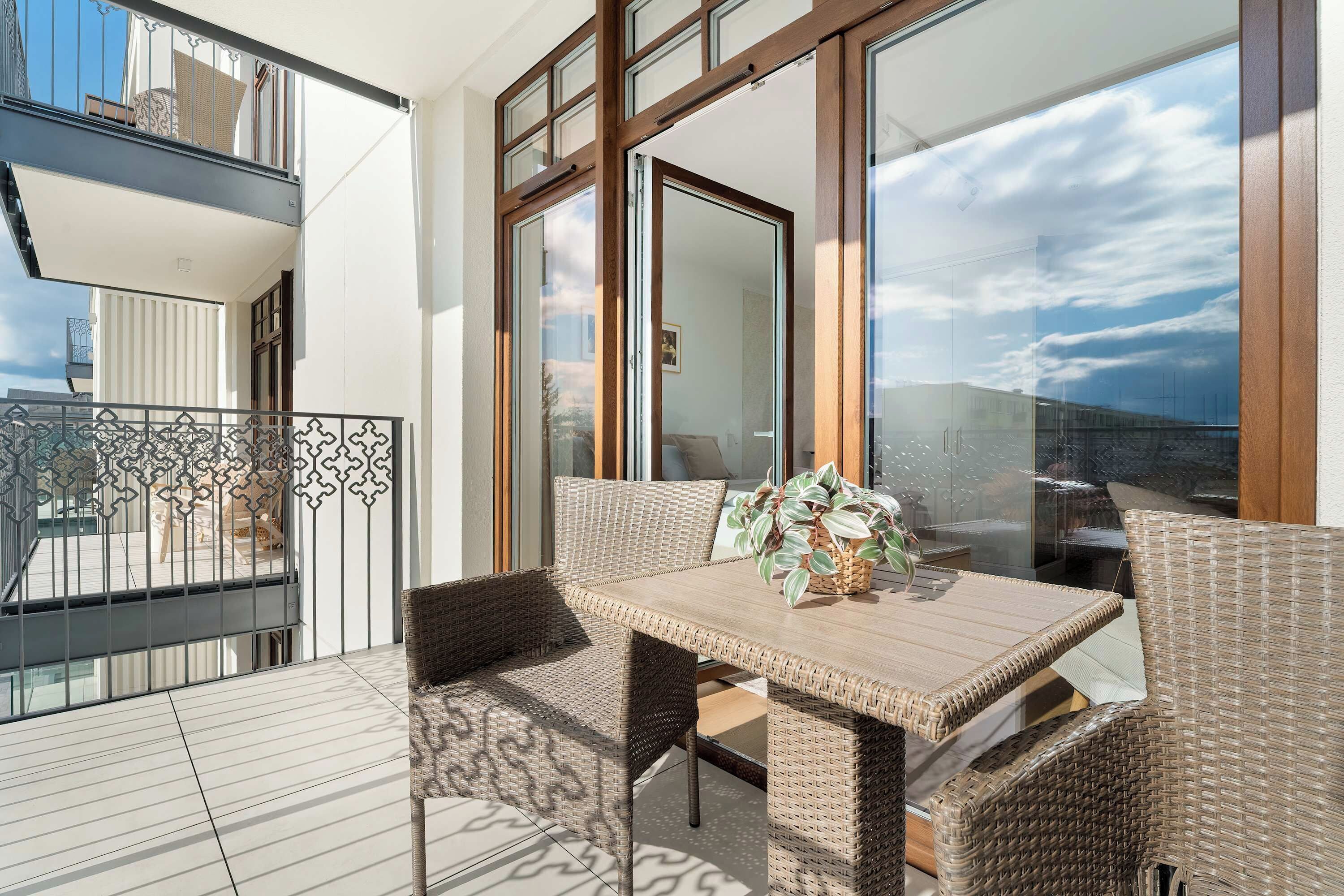 Ein Balkon mit Korbmöbeln, einem Tisch und einem Blumentopf.