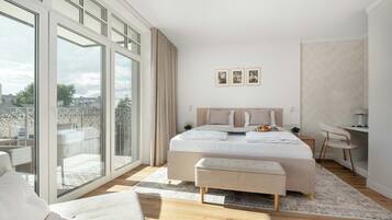 Ein modernes Schlafzimmer mit einem großen Bett, einem Schreibtisch und Blick auf die Stadt durch raumhohe Fenster.