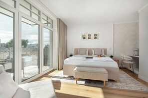Ein modernes Schlafzimmer mit einem großen Bett, einem Schreibtisch und Blick auf die Stadt durch raumhohe Fenster.