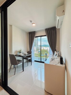 A modern hotel room with a dining area, a balcony with a view, and a marble countertop. - 1-Bedroom Plus Condo for Rent at Mira Monte, Soi Hua Hin 94 (Tambon Hua Hin)