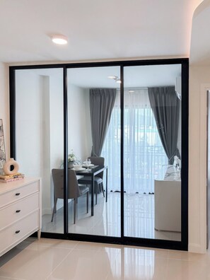 A modern dining area with a glass partition, a dining table set with plates and glasses, and a view of the city through large windows. - 1-Bedroom Plus Condo for Rent at Mira Monte, Soi Hua Hin 94 (Tambon Hua Hin)