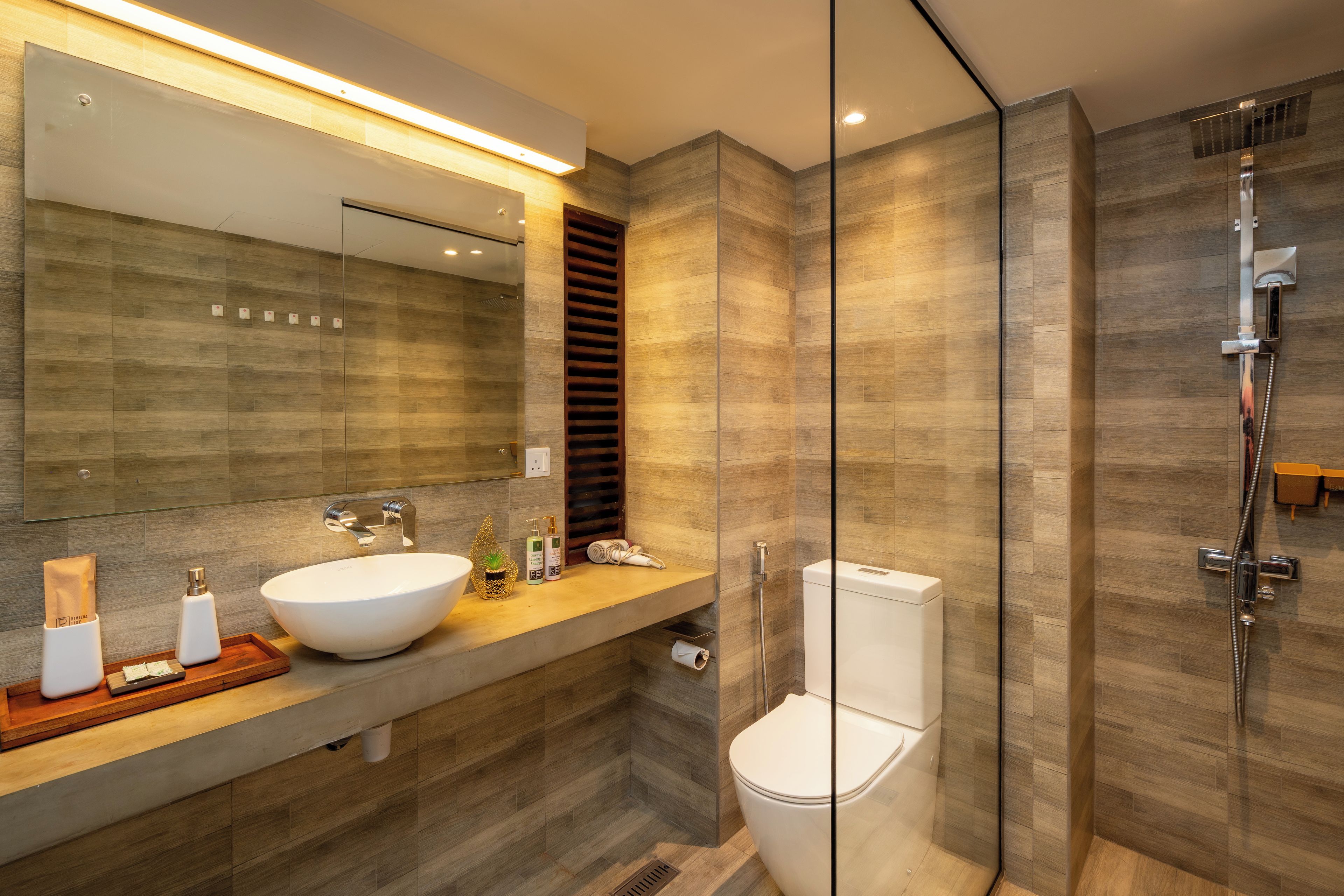 A modern bathroom with a glass-enclosed shower, a white sink, and a large mirror.
