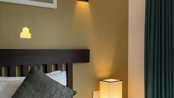 A hotel room with a bed, a nightstand with a lamp, a painting on the wall, and a window with curtains.
