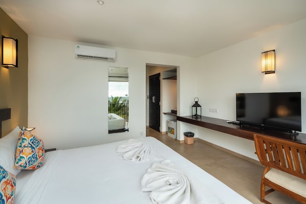 A hotel room with a bed, a TV, a desk, and a mirror. - Rivera Tide (Bentota)