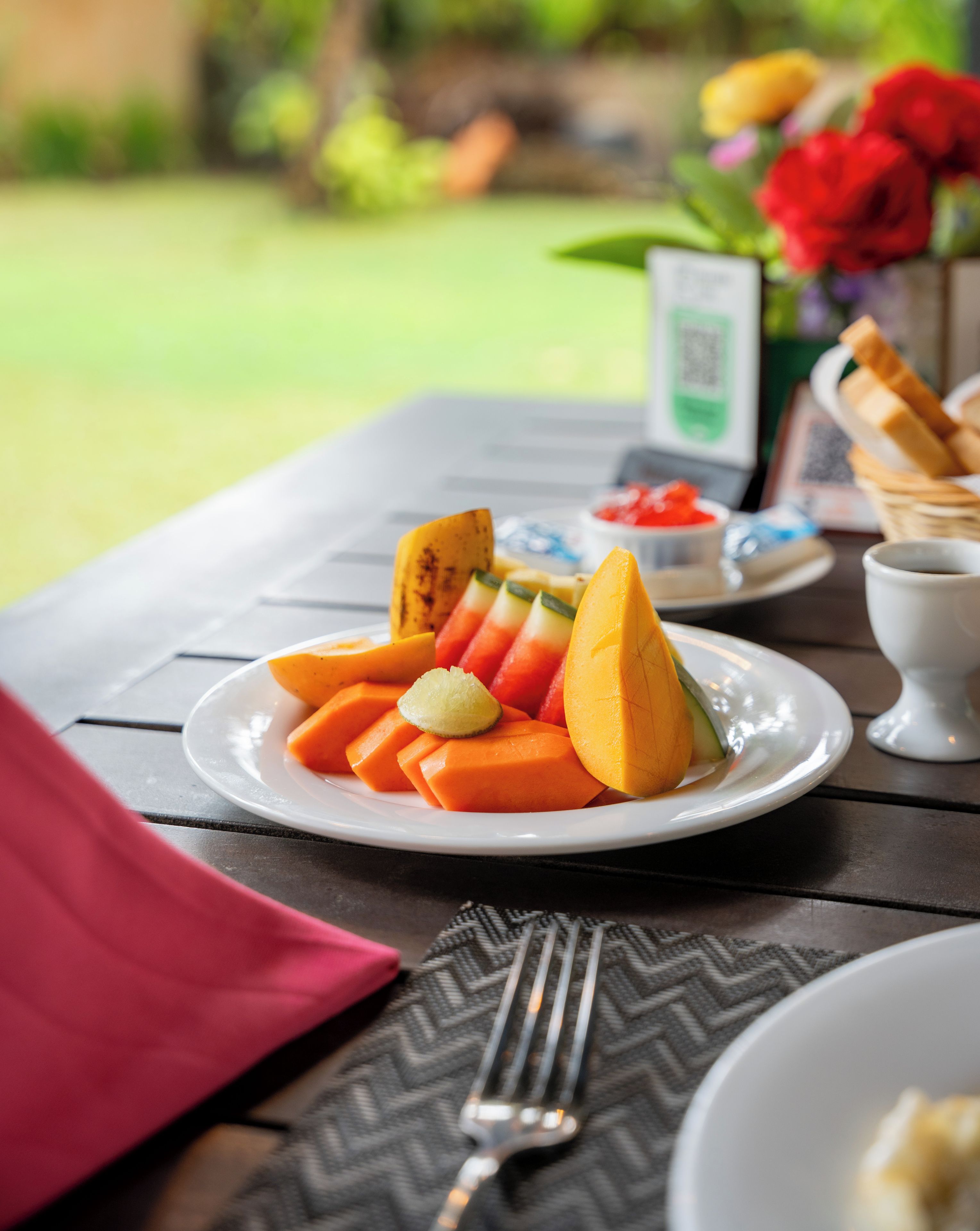 Una mesa con un plato de fruta, una servilleta, un tenedor y una taza.