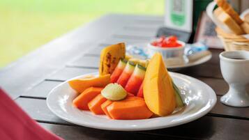 Una mesa con un plato de fruta, una servilleta, un tenedor y una taza.