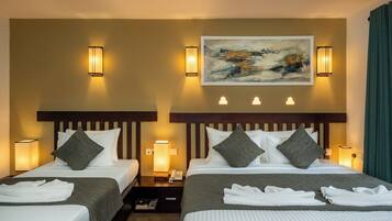 Habitación de hotel con dos camas, cada una con cabecero, lámparas de noche y un cuadro sobre las camas.