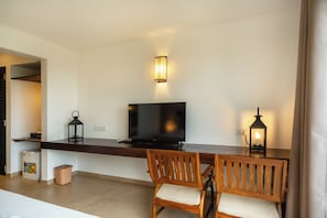 A modern living room with a flat-screen TV, wooden chairs, a dark wooden console table, and two wall-mounted lamps. - Rivera Tide (Bentota)