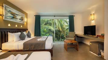 Habitación de hotel con cama, escritorio, televisión y balcón con vistas a palmeras.