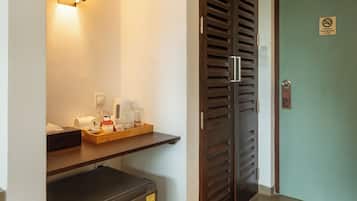 Habitación de hotel con minibar, puerta de madera con un letrero y aplique de pared.