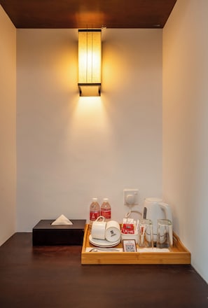 A hotel room with a bedside table, a tray with toiletries, a lamp, and a wall socket. - Rivera Tide (Bentota)