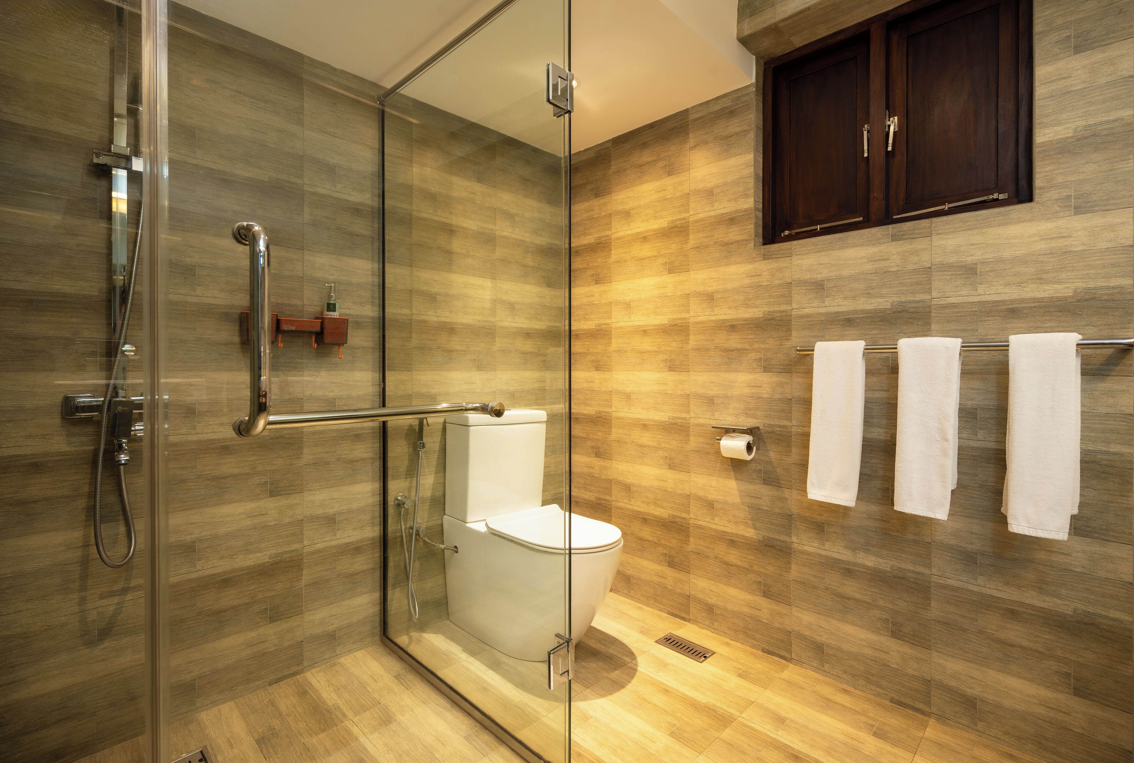 A modern bathroom with a glass-enclosed shower, a toilet, and a towel rack with towels.