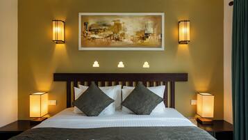 Habitación de hotel con una cama grande, dos lámparas de noche, un cuadro en la pared y una ventana con cortinas.