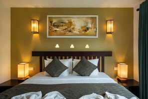 A hotel room with a large bed, two bedside lamps, a painting on the wall, and a window with curtains.