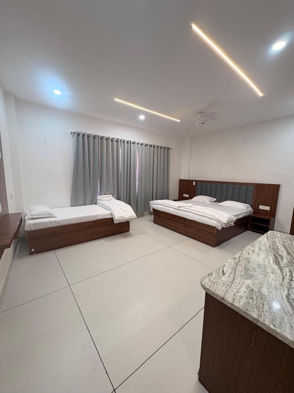 Ein Hotelzimmer mit zwei Betten, einer Marmorplatte und einem Deckenventilator.