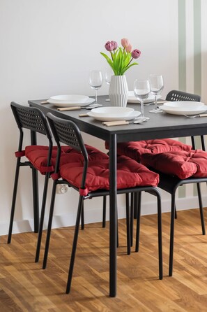 A dining table with white plates, cutlery, and a vase with flowers. - Warsaw | Pereca 2 | Comfortable Apartment | City Centre (Warszawa)