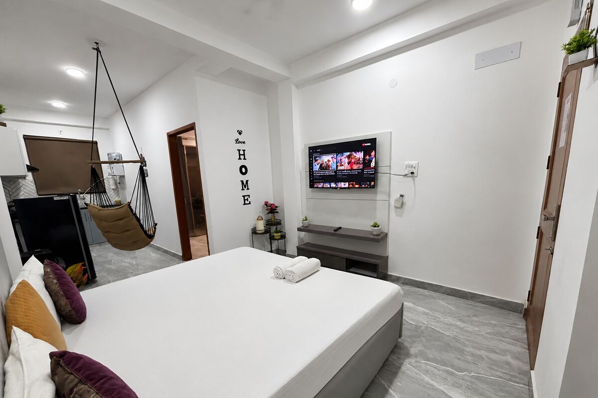 Ein modernes Schlafzimmer mit einem Bett, einem Fernseher, einem Hängesessel und einer Wand mit dem Wort 'HOME'.