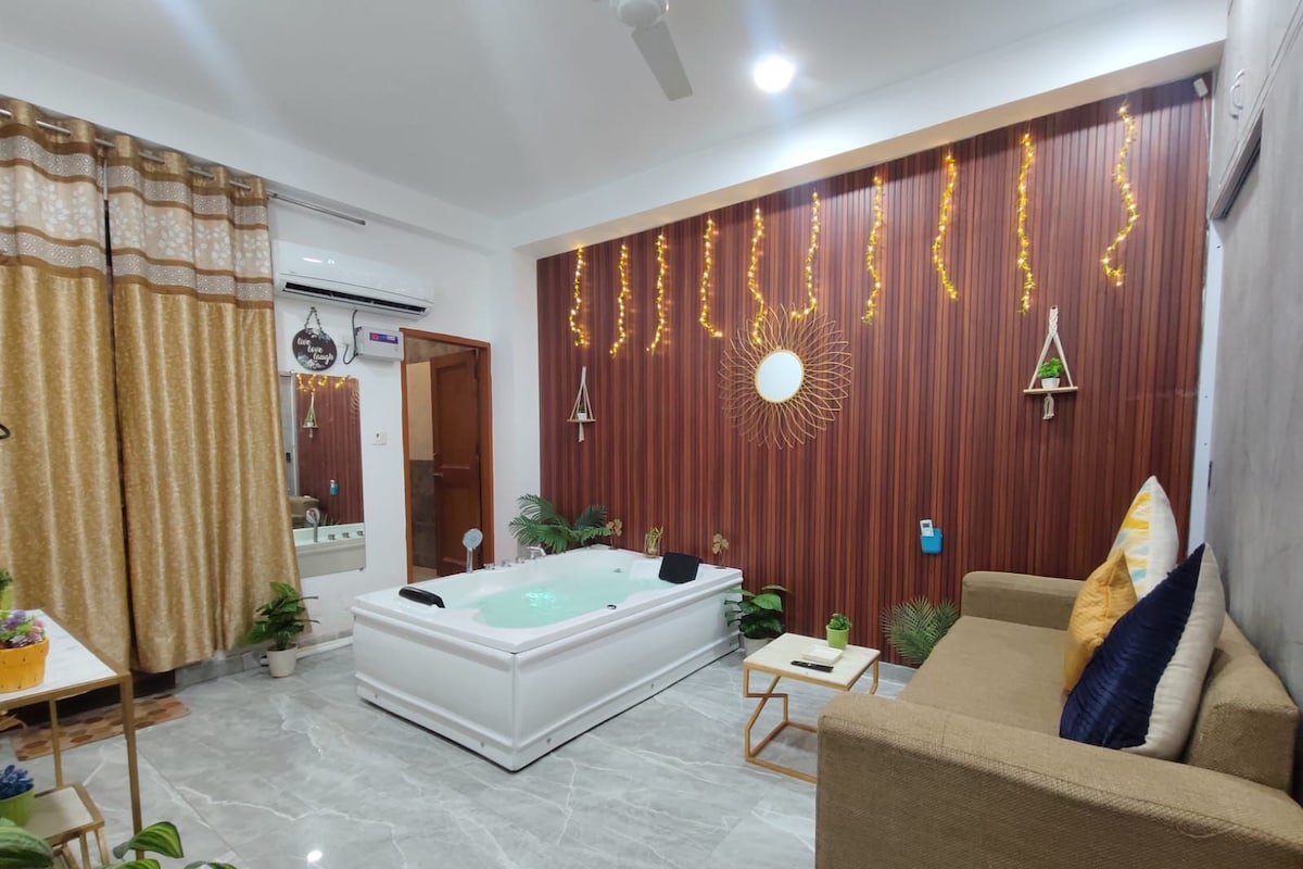 A modern living room with a large white bathtub, a beige sofa, and a wooden wall with decorative lights.