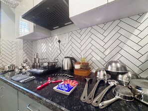 A kitchen with a herringbone tile backsplash, stainless steel appliances, and various utensils on the counter.