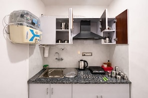 Een kleine keuken met een spoelbak, fornuis en diverse keukengerei.