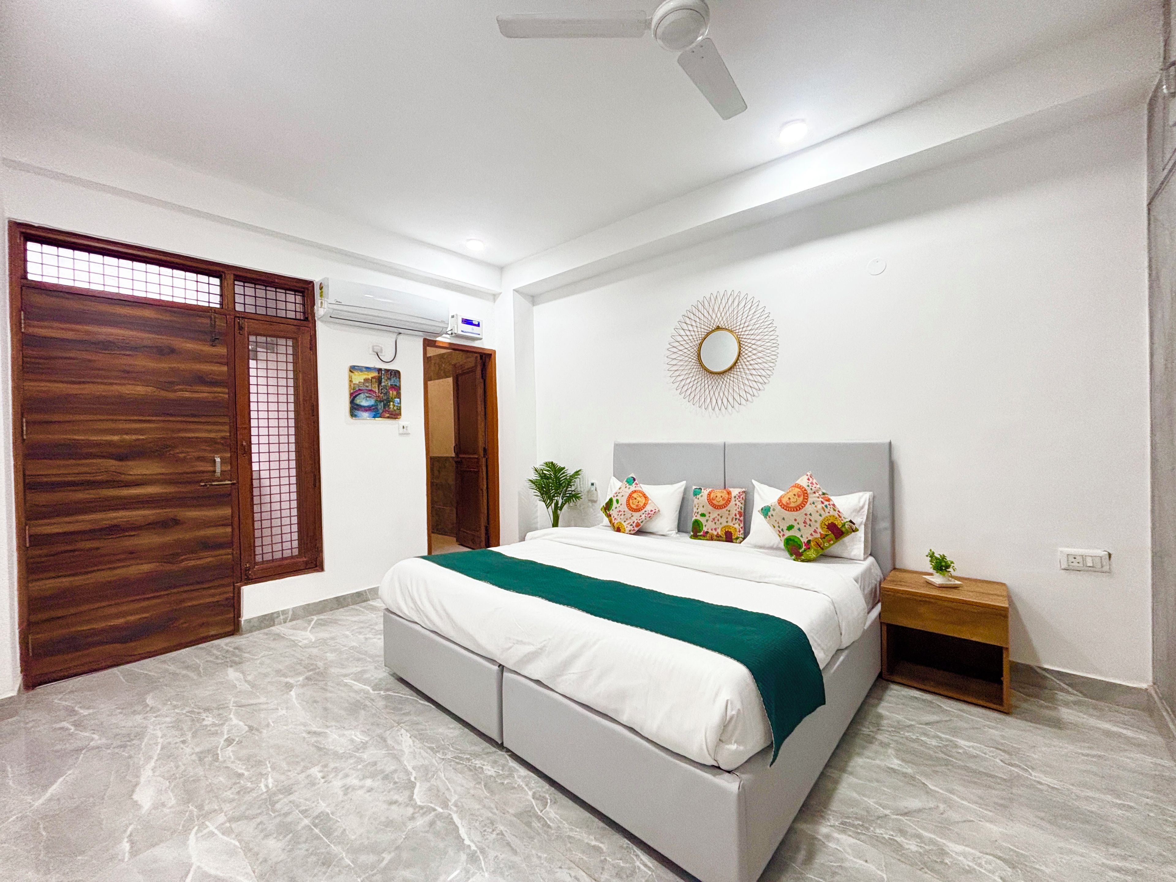 A bedroom with a bed, nightstand, and a decorative mirror on the wall.