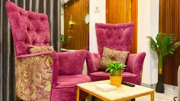 A room with two plush armchairs, a small table, and a potted plant.