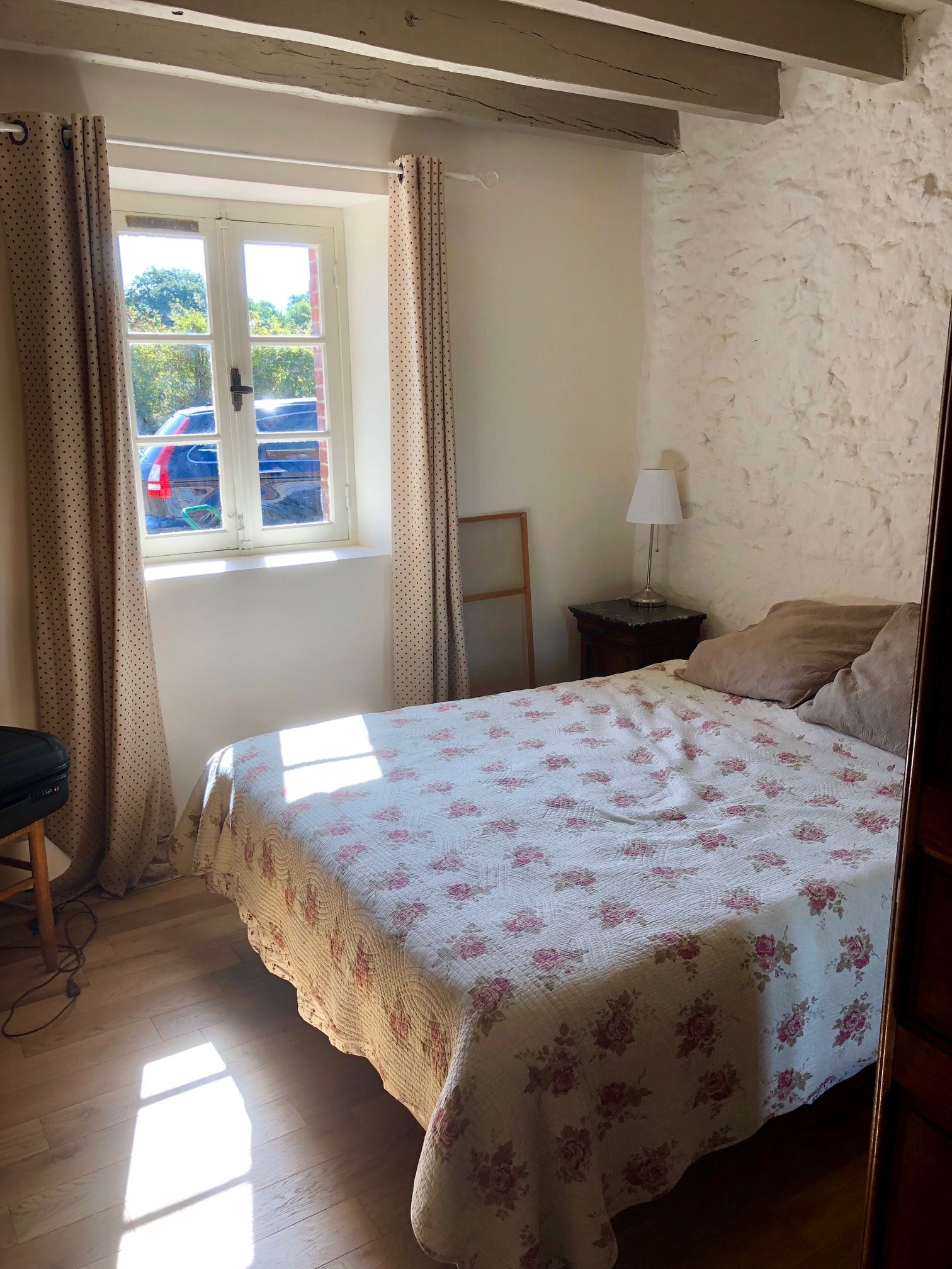 A bedroom with a bed, a window, curtains, a lamp, and a chair.