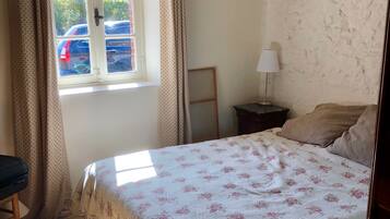 A bedroom with a bed, a window, curtains, a lamp, and a chair.