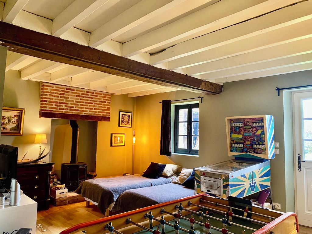 A bedroom with a brick fireplace, a bed, a foosball table, and a window with curtains.