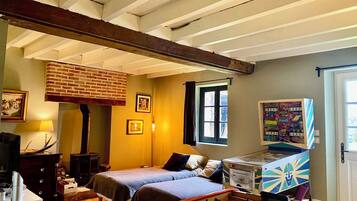 A bedroom with a brick fireplace, a bed, a foosball table, and a window with curtains.