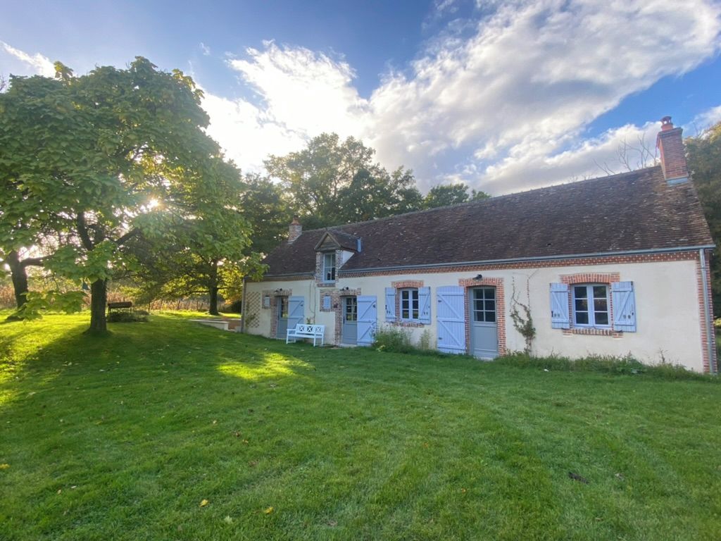 A traditional house with a brick facade, a chimney, and a well-maintained lawn.