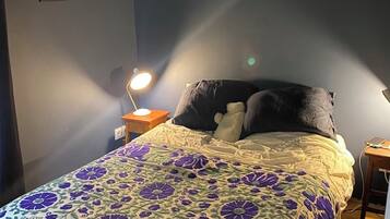 A bedroom with a bed, a nightstand, a wall with a signature, and a framed picture.