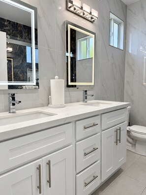 A modern bathroom with two sinks, a toilet, and a large mirror. - Serene Brand New studio with AC in charming La Palma  (La Palma)