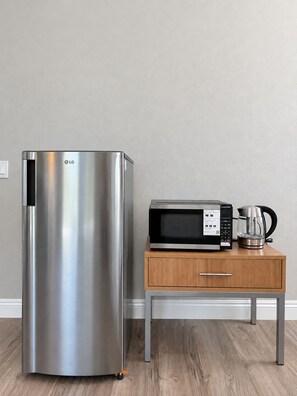 A stainless steel refrigerator next to a wooden side table with a microwave and a coffee maker. - Serene Brand New studio with AC in charming La Palma  (La Palma)