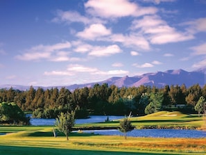 A golf course with a lake, trees, and mountains in the background. - 2-bedroom townhome in Located in Eagle Crest Resort, with resort amenities. (Redmond)