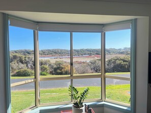 A room with a large bay window overlooking a landscape with trees and a body of water. - My Time @ Robe - Views- Wood fire (Robe)