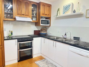 A kitchen with wooden cabinets, a microwave, a Bosch dishwasher, and a stove. - My Time @ Robe - Views- Wood fire (Robe)