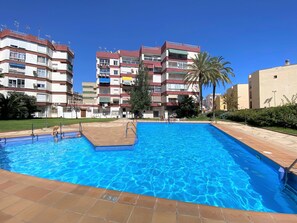 A swimming pool with tiled edges, surrounded by multi-story residential buildings with balconies and air conditioning units. - Apartment in Nerja With Sea Views & Pool (Nerja)