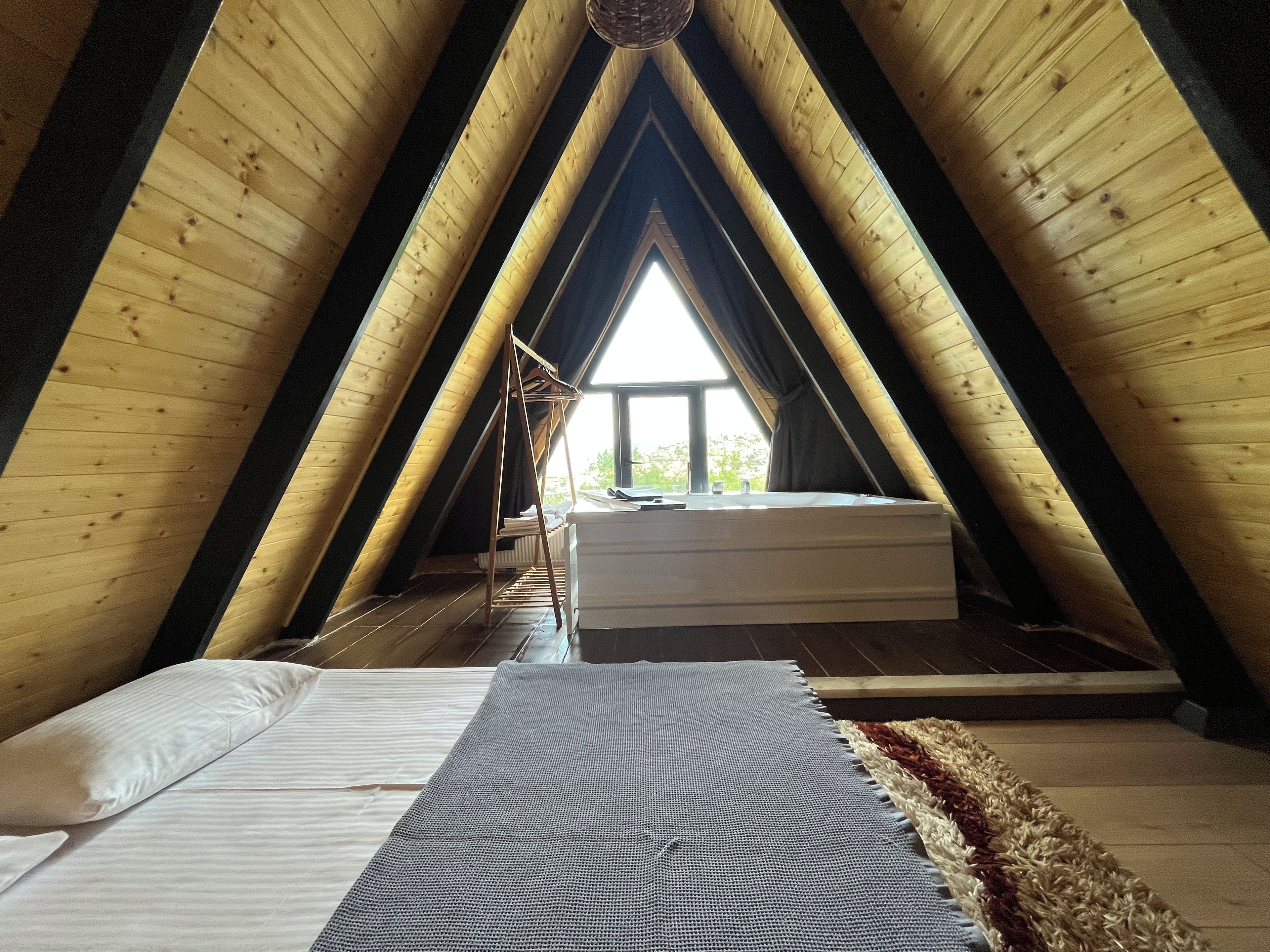 Ein Schlafzimmer im Dachgeschoss mit hohen Decken, geneigtem Dach, einem Bett, einem Fenster und einer Heizung.