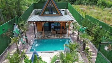Une maison avec une piscine, entourée de verdure et dotée d’un terrain clôturé.