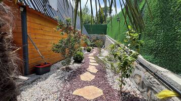A garden pathway with stepping stones, a wooden fence, and a green hedge.