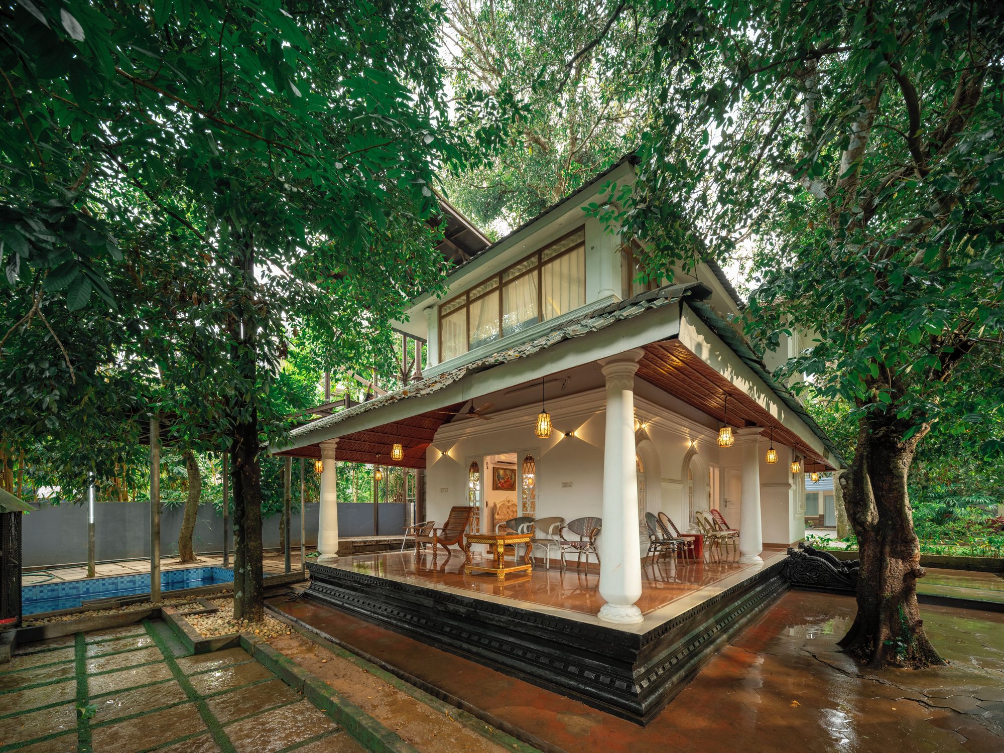 A two-story house with a covered porch, a swimming pool, and a garden.