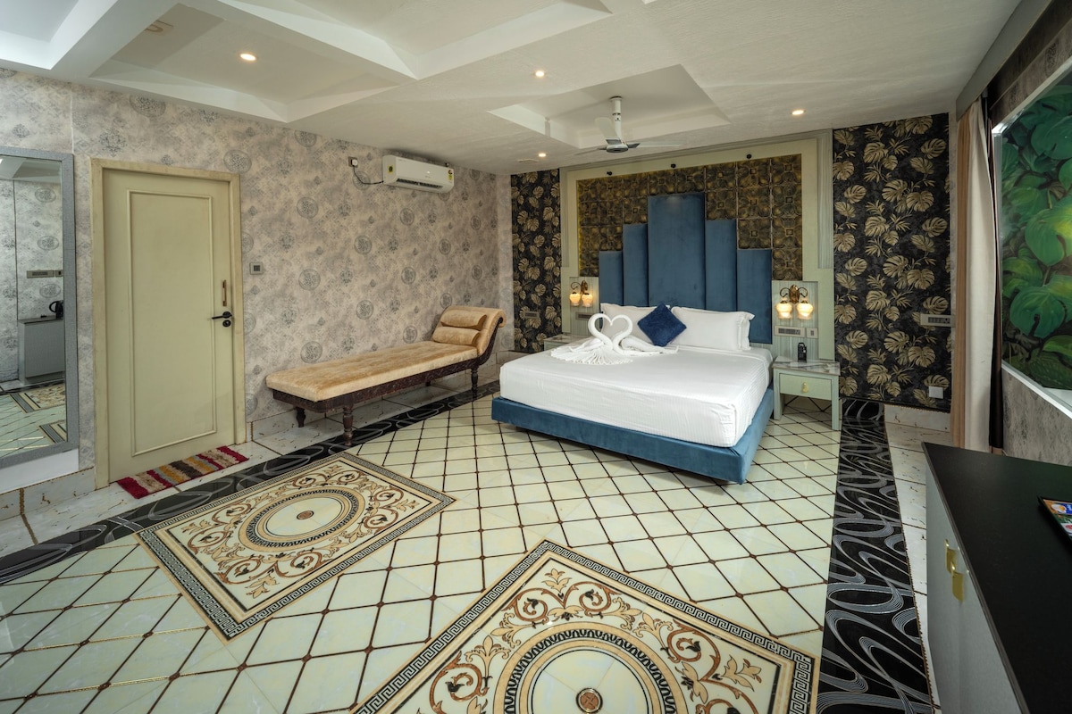 A hotel room with a bed, a bench, a mirror, a door, and a wall with a decorative pattern.