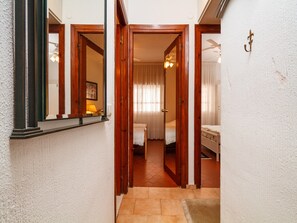 Ein Flur mit Holztüren, die zu einem Schlafzimmer mit einem Bett und einem Nachttisch führen.