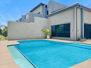 Ein modernes Haus mit Schwimmbad, großen Fenstern und Flachdach.